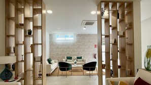 Een moderne woonkamer met een bank, twee fauteuils, een salontafel en een boekenkast.
