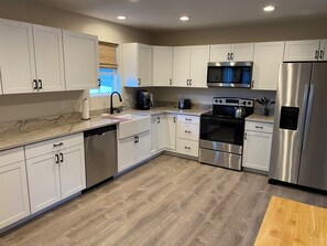 Une cuisine moderne avec des meubles blancs, des appareils en acier inoxydable et un plancher en bois.