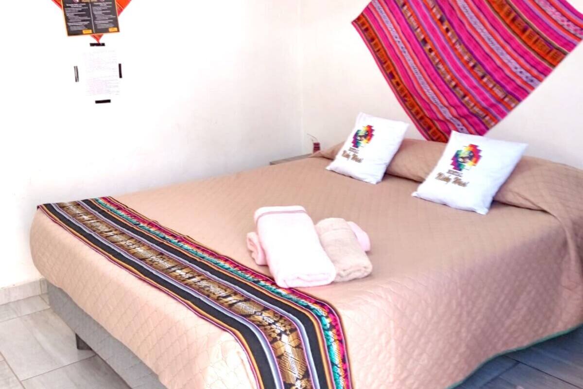 Ein Bett mit einer gestreiften Decke, zwei Kissen und einem kleinen Teppich auf dem Boden.