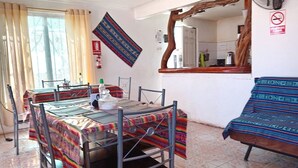 Een eetgedeelte met een tafel voor vier personen, een stoel, een ventilator en een keuken in de achtergrond.