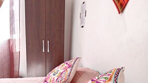 Een slaapkamer met een bed, twee kussens, een kledingkast en een object aan de muur.