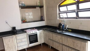 A kitchen with a stove, sink, and cabinets. - Seaside House (Parque Balneario Comodoro Mongaguá)