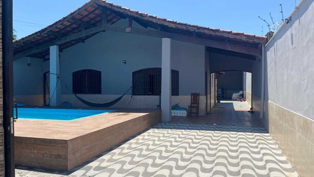 A covered outdoor area with a pool, a hammock, and a patterned floor. - Seaside House (Parque Balneario Comodoro Mongaguá)