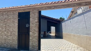 A building with a tiled roof, a wooden door, and a patterned floor. - Seaside House (Parque Balneario Comodoro Mongaguá)