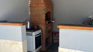 A kitchen with a brick oven, a gas stove, and a sink. - Seaside House (Parque Balneario Comodoro Mongaguá)