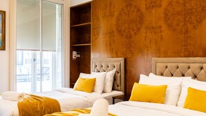 Habitación de hotel con dos camas, una pared de madera y vistas a través de un ventanal.
