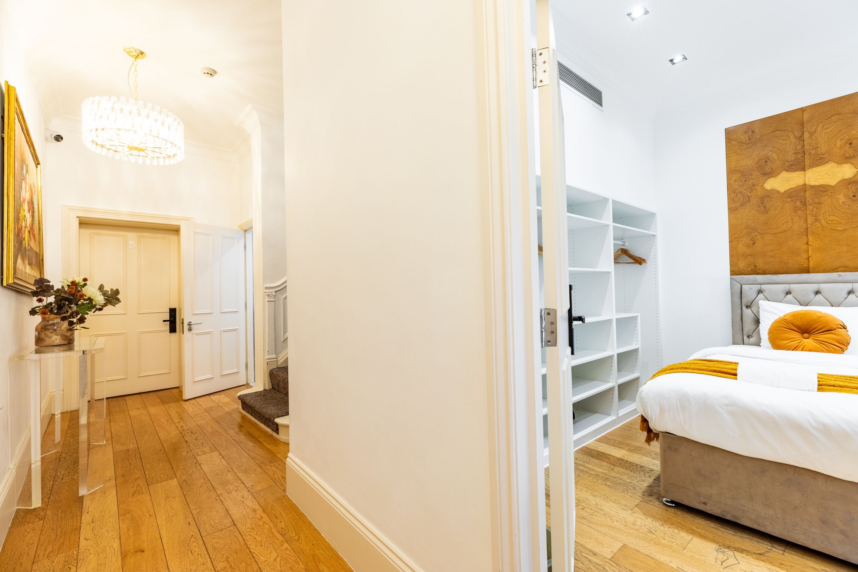 Een slaapkamer met een bed, een houten hoofdbord, een nachtkastje en een inbouwkast.