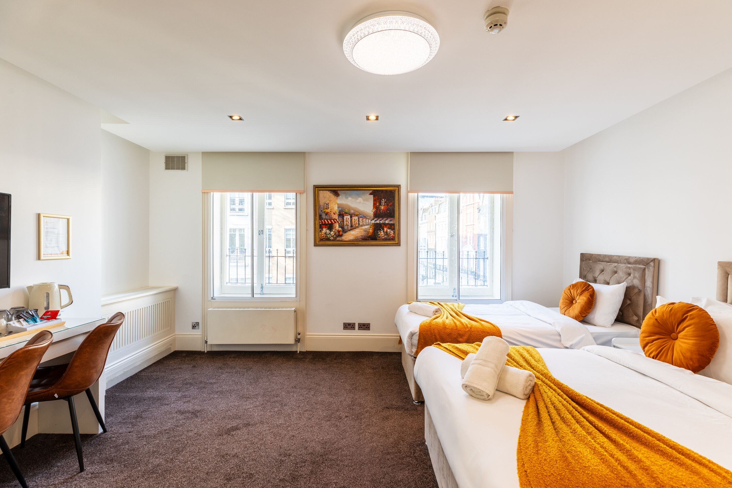 Une chambre d’hôtel avec un lit, un bureau, une chaise et un tableau au mur.