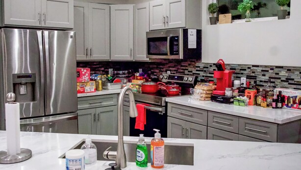 A modern kitchen with stainless steel appliances, a marble countertop, and red chairs. -  Charming 3-bedroom house with WiFi and AC in Houston - Unit #1 (Houston)