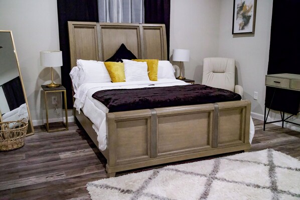 A bedroom with a wooden bed, two bedside tables with lamps, a chair, a desk, and a large mirror. -  Charming 3-bedroom house with WiFi and AC in Houston - Unit #1 (Houston)