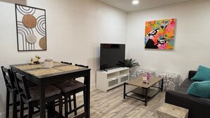 A modern living room with a dining area, a flat-screen TV, and a ceiling fan. - St. Pete 5th Ave Oasis (St. Petersburg)