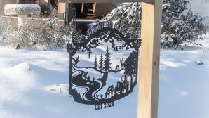 En träskylt med en vinterscen och texten ”Grundat 1924”, placerad utomhus i en snöig miljö.