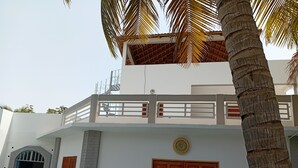 A two-story building with a balcony, a wooden door, and a small window. - Melia Beach (Mbour)