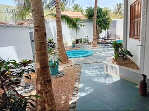 A courtyard with a swimming pool, palm trees, and a tiled walkway. - Melia Beach (Mbour)