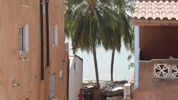 Un estrecho callejón flanqueado por edificios, con una palmera y vista al mar.