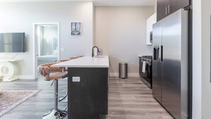 A modern kitchen with a central island, stainless steel appliances, and a minimalist design. - Chic Condo by NYC w Rooftop & Parking on Premises (Jersey City)