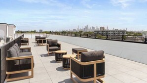A rooftop terrace with outdoor seating, a city skyline view, and a railing. - Chic Condo by NYC w Rooftop & Parking on Premises (Jersey City)