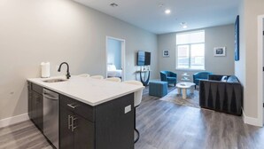 Una cocina moderna con una isla central, un área de comedor con una mesa redonda y un espacio de estar con sillas azules.