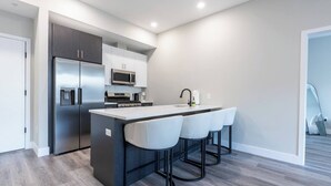 Una cocina moderna con una isla central, electrodomésticos de acero inoxidable y taburetes de bar.