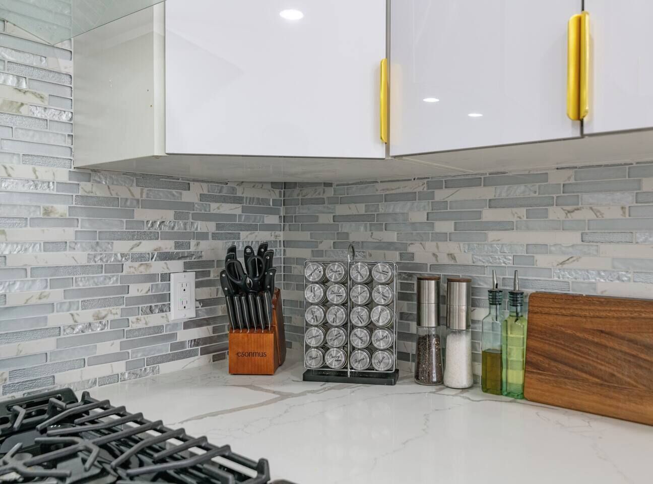 Una cocina con armarios blancos, salpicadero de mármol y diversos utensilios y electrodomésticos.