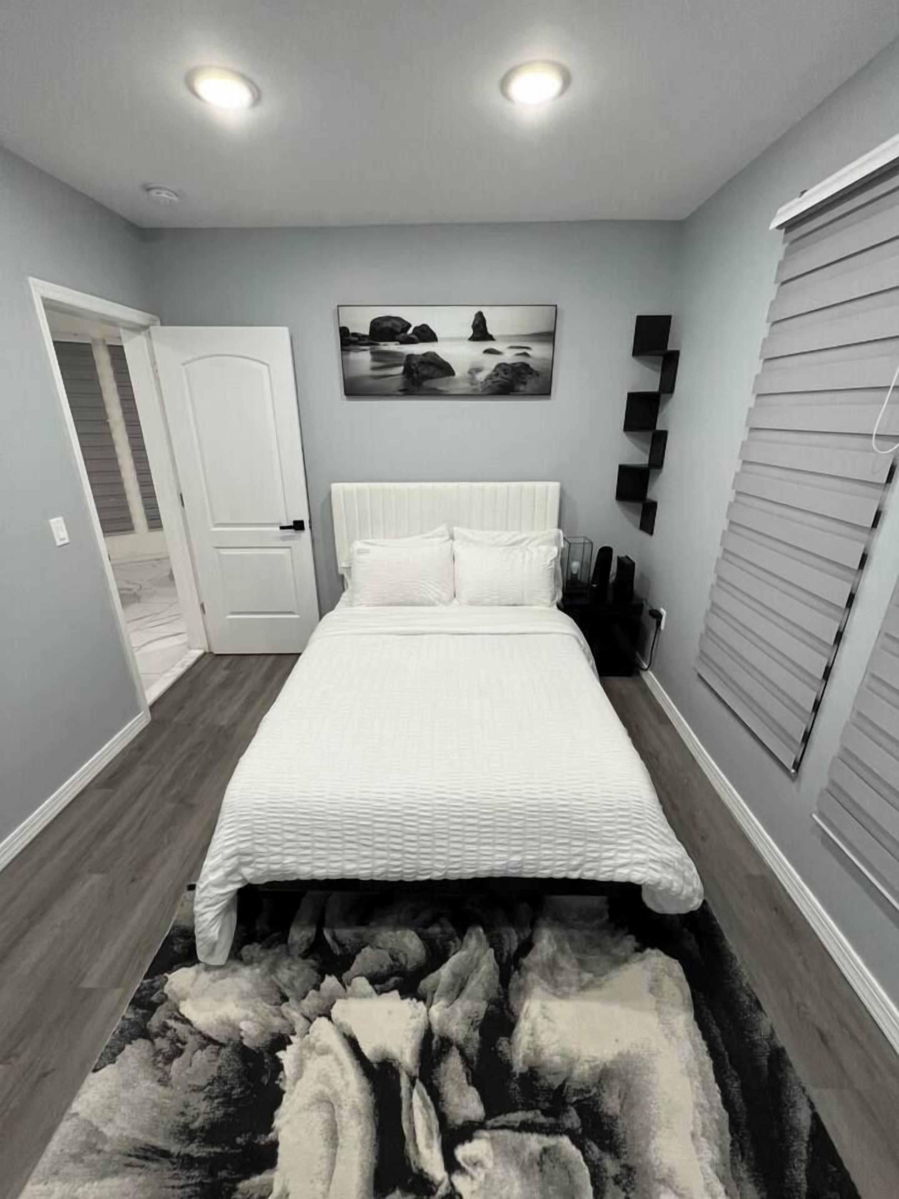 Un dormitorio con cama, un cuadro, una puerta y un ventanal.