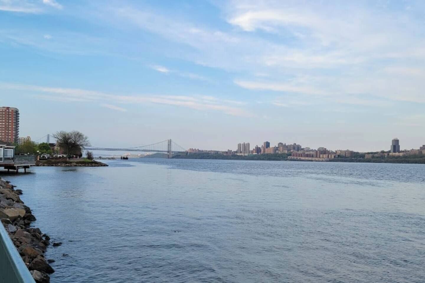 Un río con un puente y el perfil urbano de una ciudad al fondo.