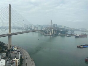 A cable-stayed bridge spanning a river with buildings and boats nearby.