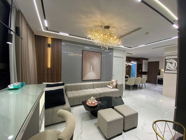 A modern living room with a glass coffee table, beige sofas, and a chandelier.