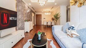 Un saló modern amb televisió de pantalla plana, zona de menjador amb un candelabrum i un sofà amb coixins decoratius.