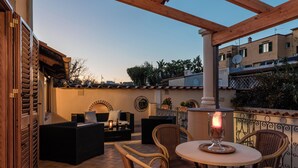 An outdoor patio area with wicker furniture, a table with a candle, and a view of the cityscape in the background. - Domus Aenaria - Spacious Villa - Prime location close to beaches and shops (Ischia)