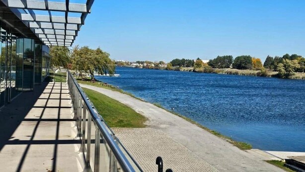 A riverside walkway with a metal railing, a paved path, and a clear view of the water. - Niagara Falls Area  Hidden Gem-Luxury, Cozy Canal-Side Home, Niagara Area's Hidden Gem- JNShortstay (Welland)
