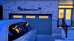 A building with a garage door and a driveway. - Niagara Falls Area  Hidden Gem-Luxury, Cozy Canal-Side Home, Niagara Area's Hidden Gem- JNShortstay (Welland)