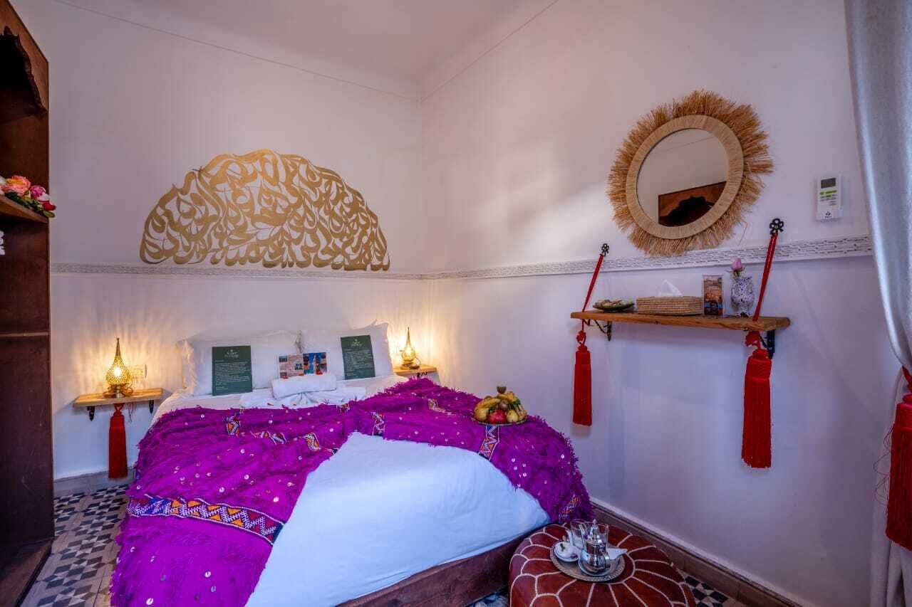 Una habitación con una cama, un espejo en la pared y una estantería con objetos decorativos.