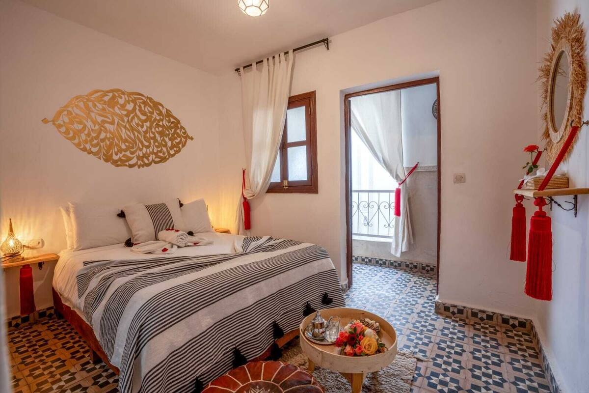 Un dormitorio con cama, mesita de noche y una pequeña mesa con bandeja.