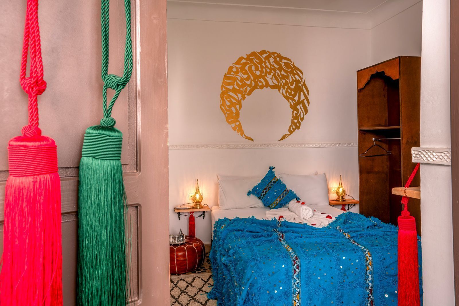 A room with a bed, two bedside tables, a wall-mounted mirror, and a wardrobe.