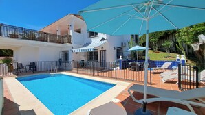 Ein zweigeschossiges Haus mit Swimmingpool, Gartenmöbeln und einer überdachten Terrasse.