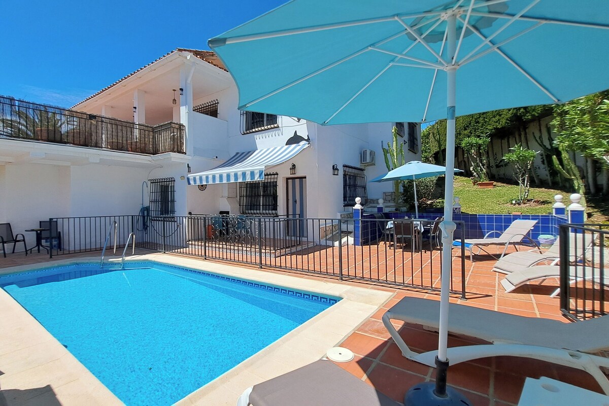 A two-story house with a swimming pool, outdoor furniture, and a covered patio area.