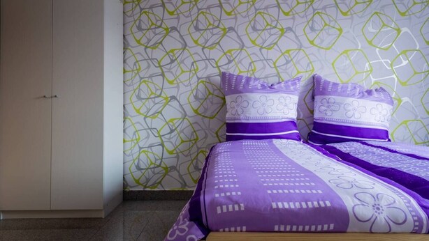 Un dormitorio con cama, dos almohadas y un armario.