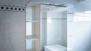 Un baño moderno con un espejo grande, un inodoro y un lavabo.