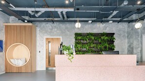 Een modern receptiegedeelte met een sproeteleffect aanrechtblad, een wand van houten latten en een groene verticale tuin.
