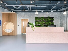 A modern reception area with a speckled countertop, a wooden slat wall, and a green vertical garden.