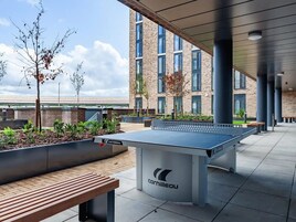 An outdoor area with a ping pong table, benches, and planters.