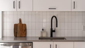 A modern kitchen with white cabinets, a stainless steel sink, and a wooden cutting board. - Maison Rasco • One-Bedroom Apartment • Old Montreal • Central • Self Check-In Access • Full Kitchen • Pet Friendly • Wi-Fi • AC (Montreal)