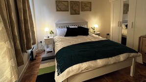 Un dormitorio ordenado con cama, mesitas de noche y un armario.