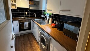 Cocina compacta con lavadora, microondas y fregadero.