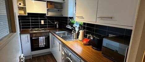 A compact kitchen with a washing machine, a microwave, and a sink.