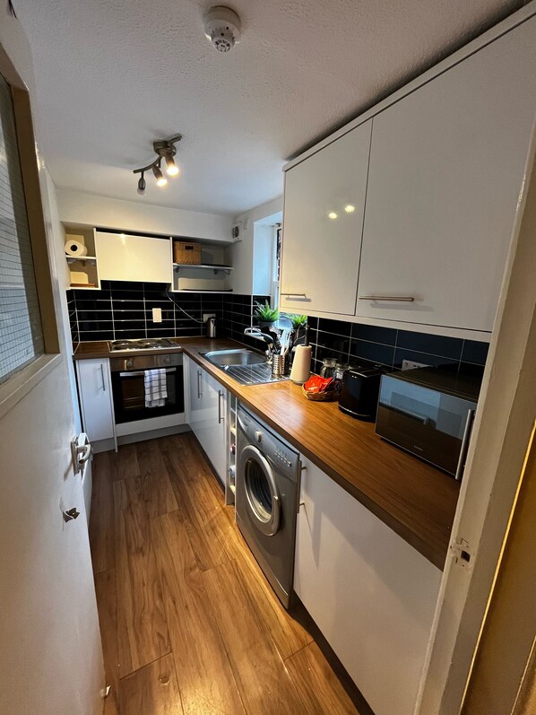 A compact kitchen with a washing machine, a microwave, and a sink.