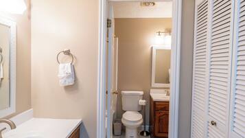 A bathroom with a toilet, sink, and mirror.