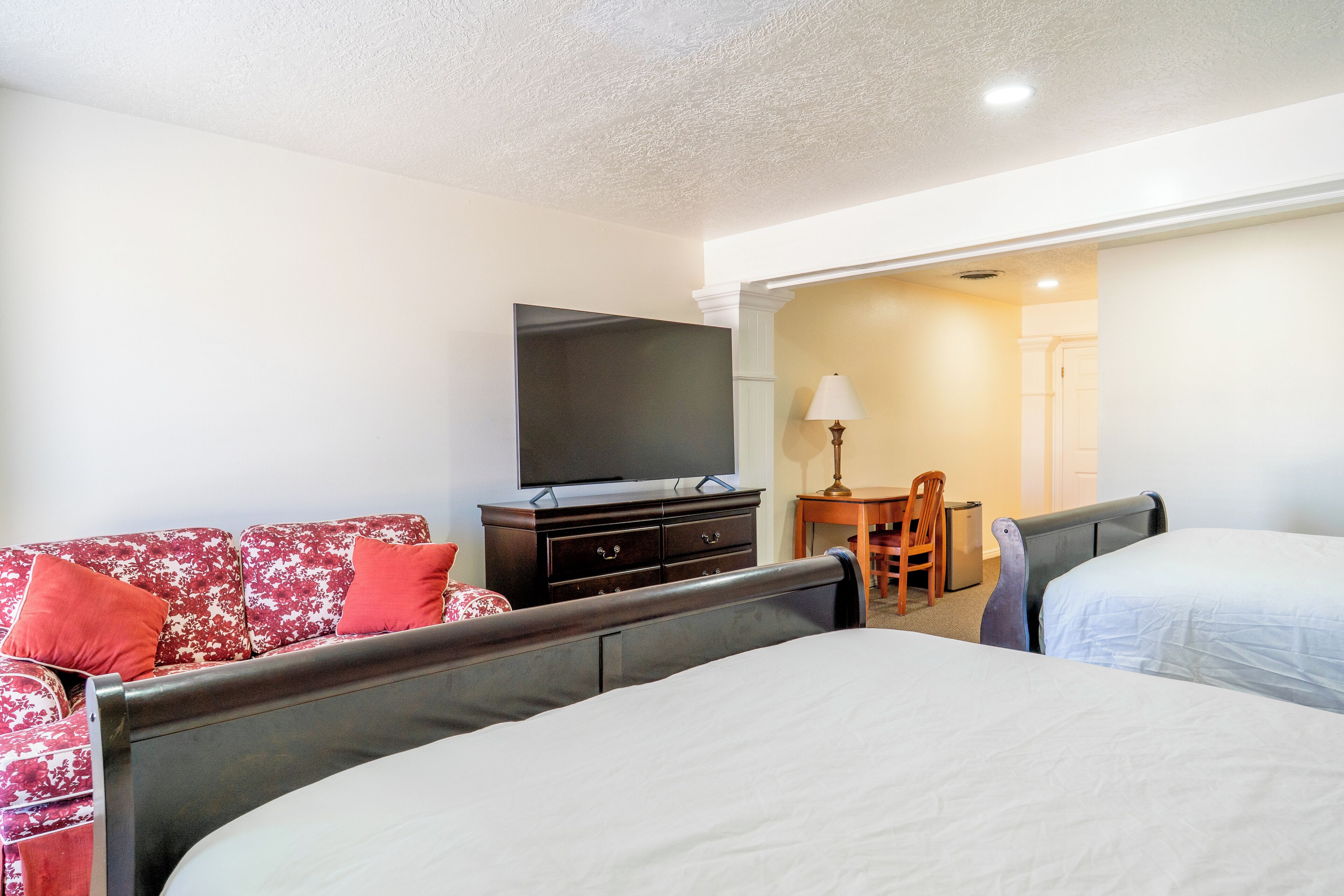 Une chambre d’hôtel avec deux lits, une télévision, un canapé, un bureau et une chaise.