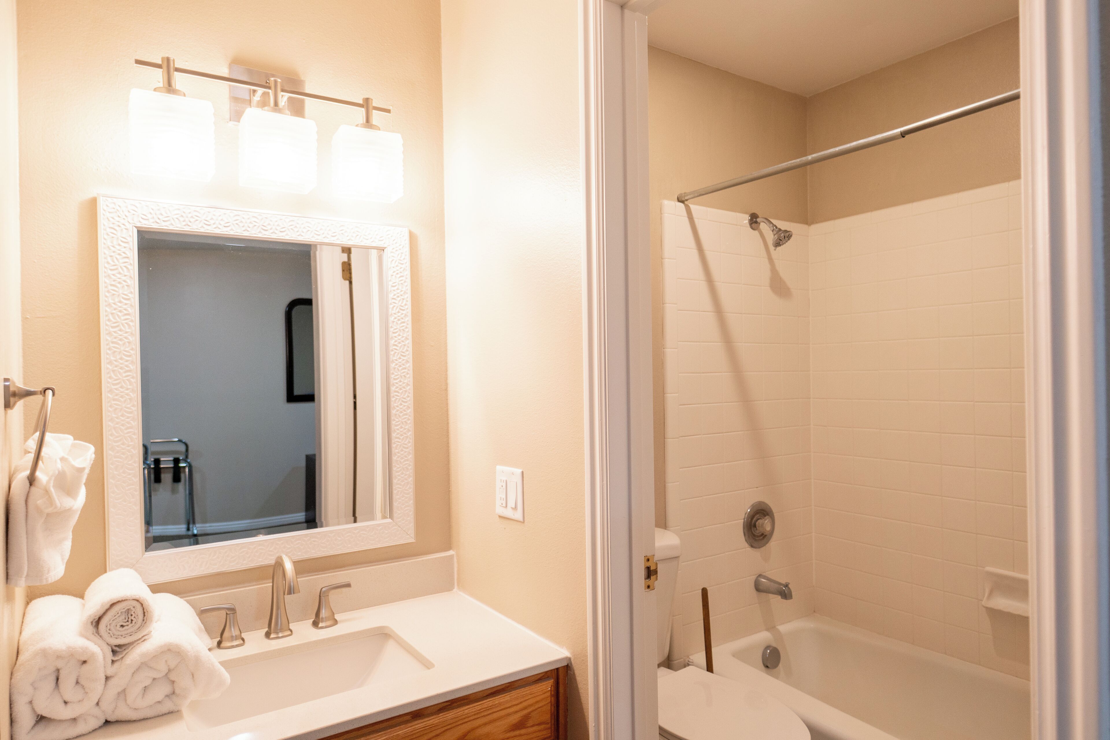 A bathroom with a sink, mirror, and shower.